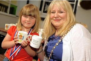 Above, Sophie, 4, is presented with her jubilee mug by mayor of Hayle Jayne Ninnes, and below, the mayor cuts the special jubilee cake at Angarrack.